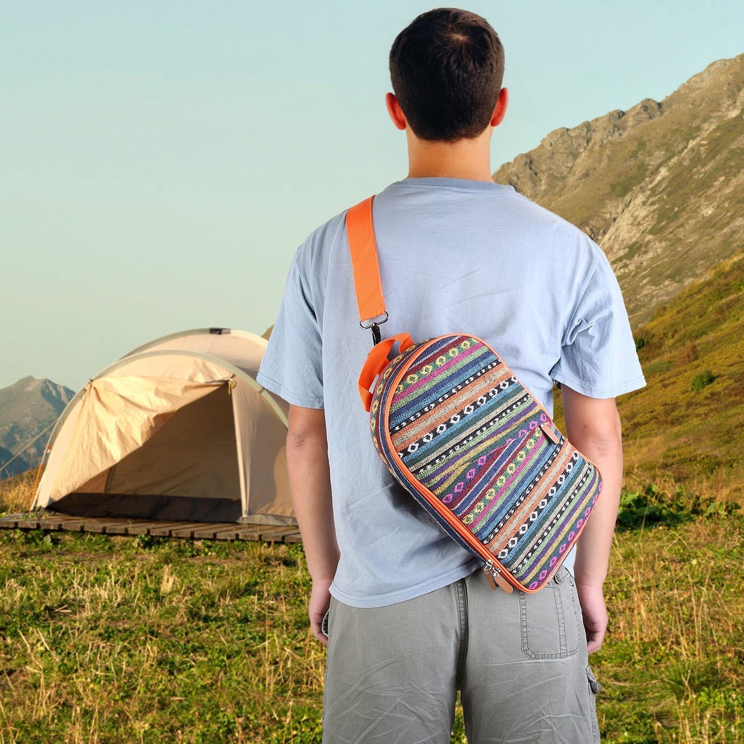 Person in a camping environment carrying a Camping Cooking Utensil Kit Portable Picnic Cookware bag at a tent.
