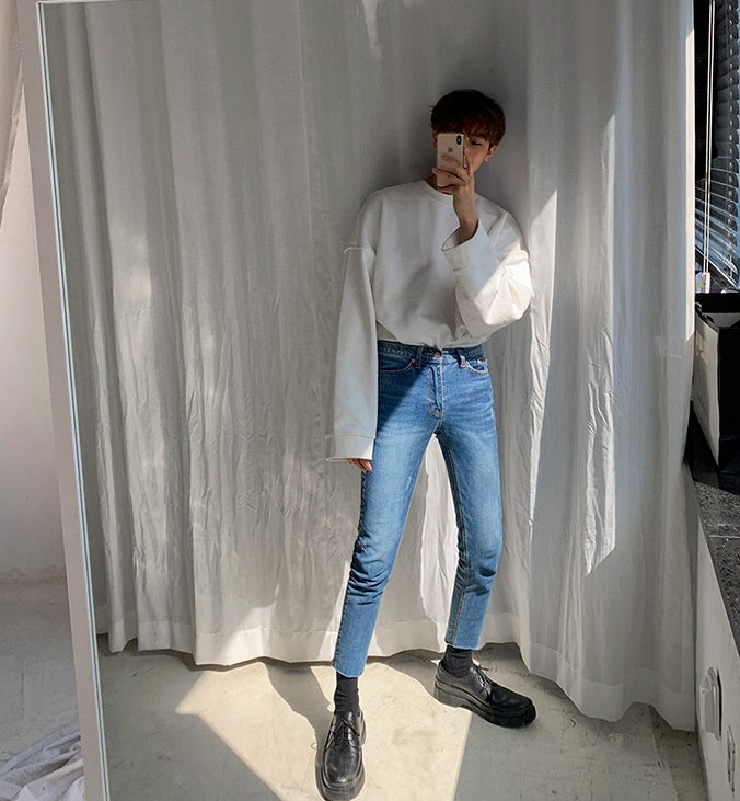 Round Neck Sweater Men's And Women's worn with blue jeans in a stylish indoor setting.
