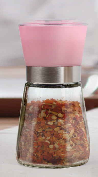 Creative kitchen appliances hand glass grinder with pink top and chili flakes inside.