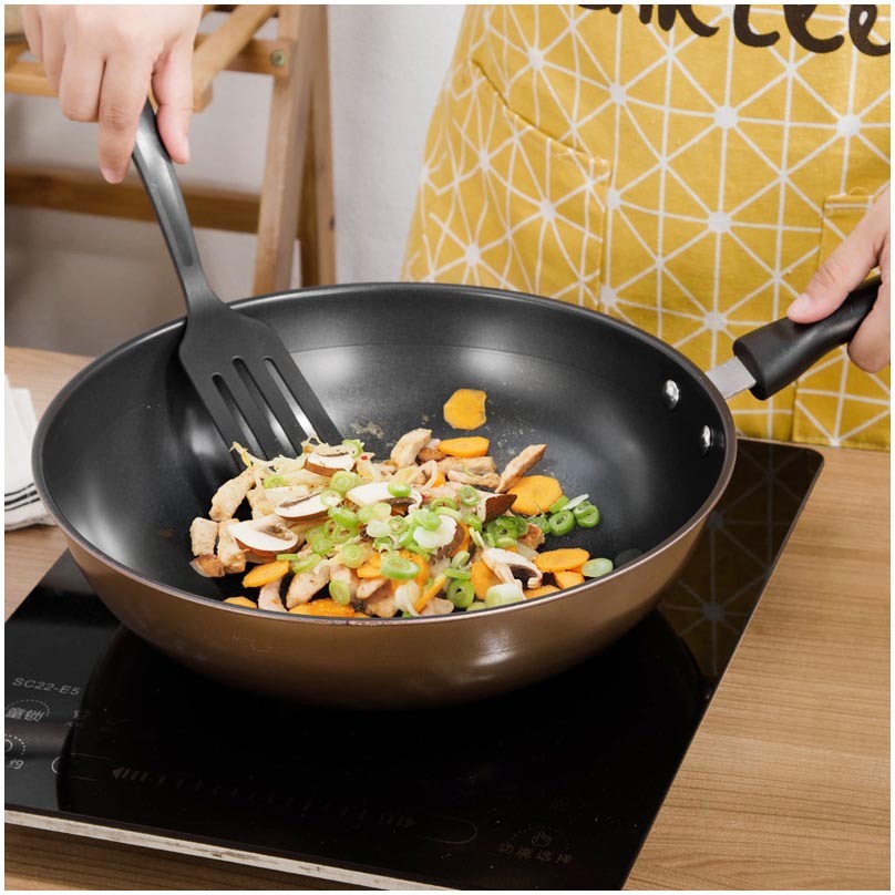 Set Of Pot Kitchen Cookware Cooking Pots with vegetables being cooked in a black frying pan on a stovetop.