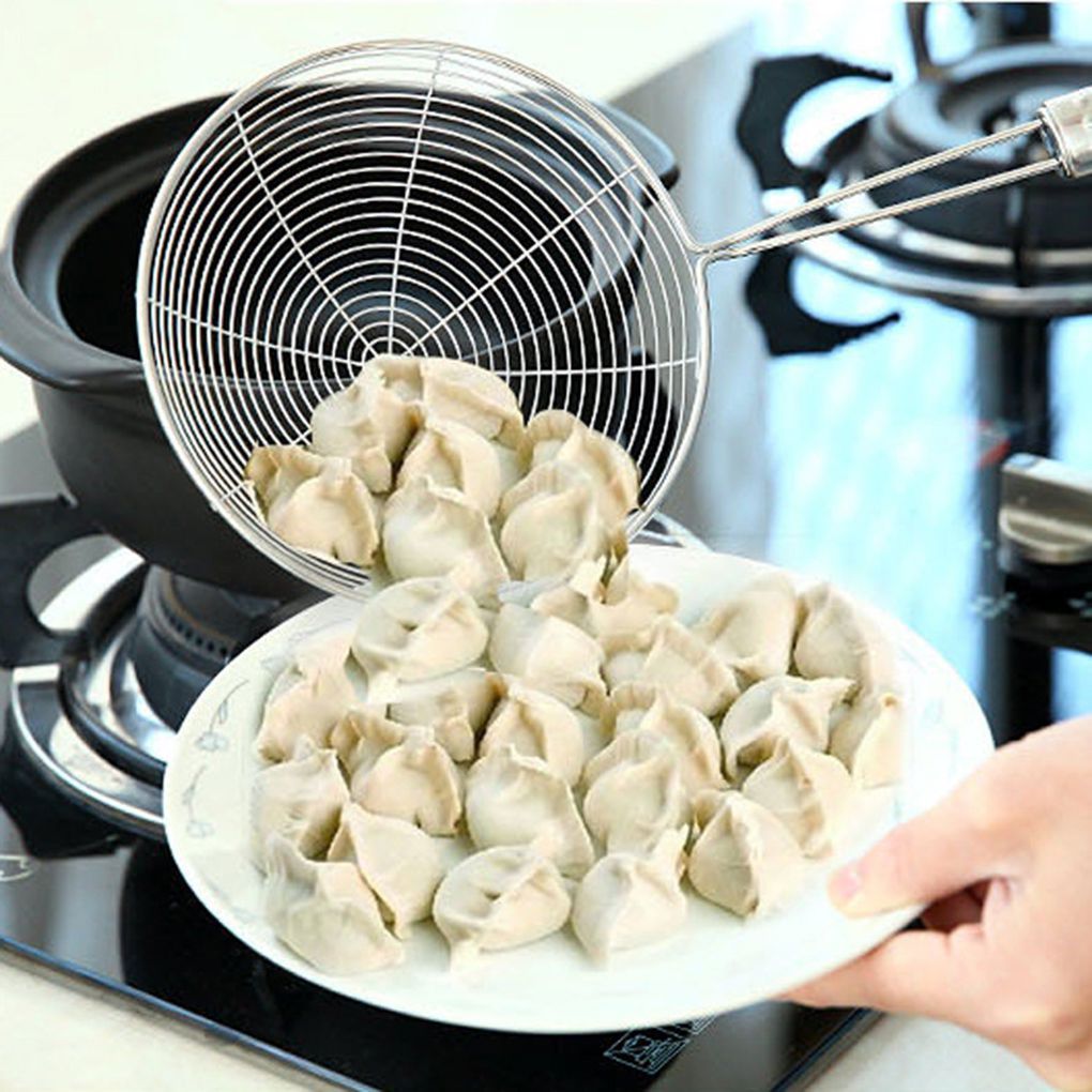 Kitchen Cooking Utensils Net Drain holding cooked dumplings over a plate on a stove.