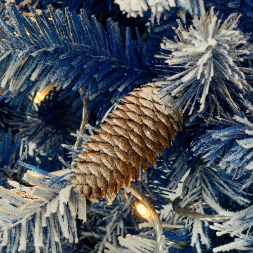 Close-up of a snow-dusted pine cone on a pre-lit Christmas tree artificial Christmas with blue branches.